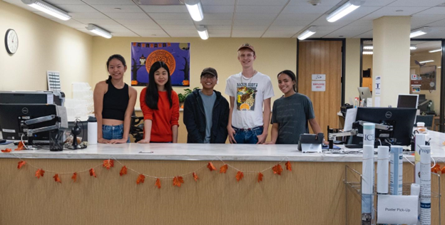 A group of people standing in front of a counterDescription automatically generated