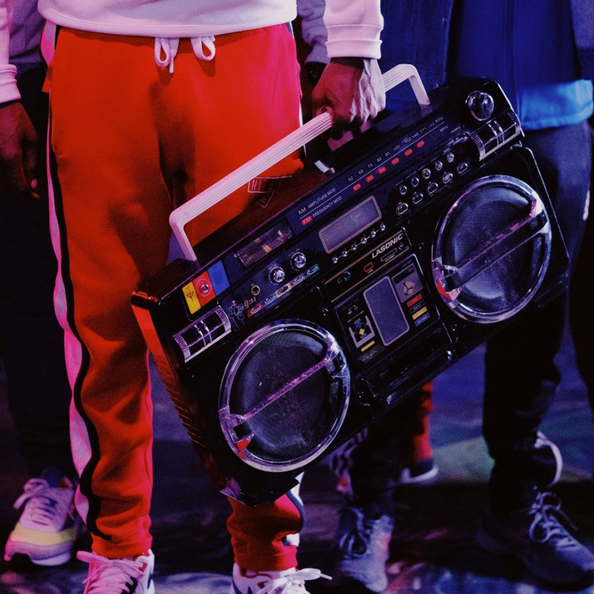 A person wearing red sweat pants holds a boombox