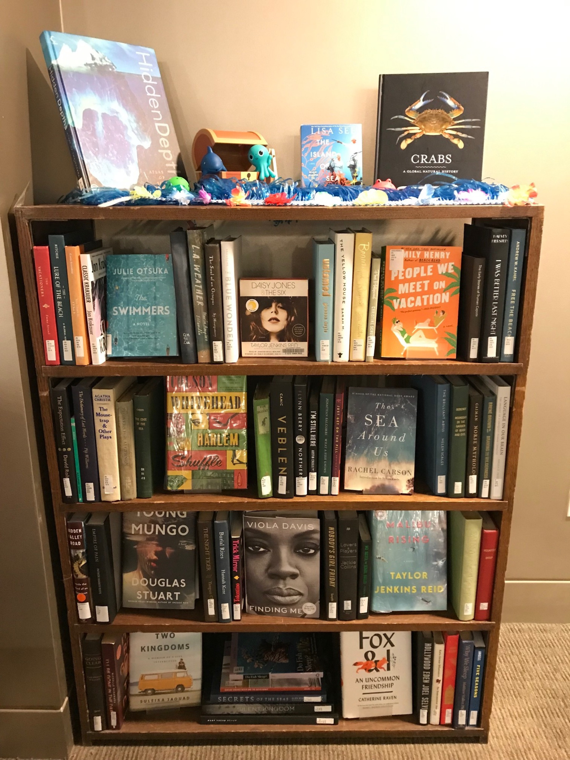 Book display with summer reads on display, some facing out and some spine-out on the bookcase