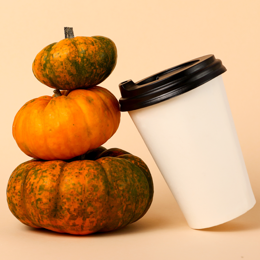 three stacked pumpkins with a hot beverage to-go cup